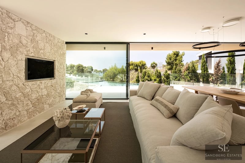 Exterior view of a modern house with an infinity pool. Features include minimalist architecture, large windows, and a lush garden.