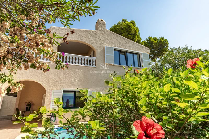 Large pool with sun loungers, surrounded by modern architecture and lush greenery. Open spaces and contemporary design.