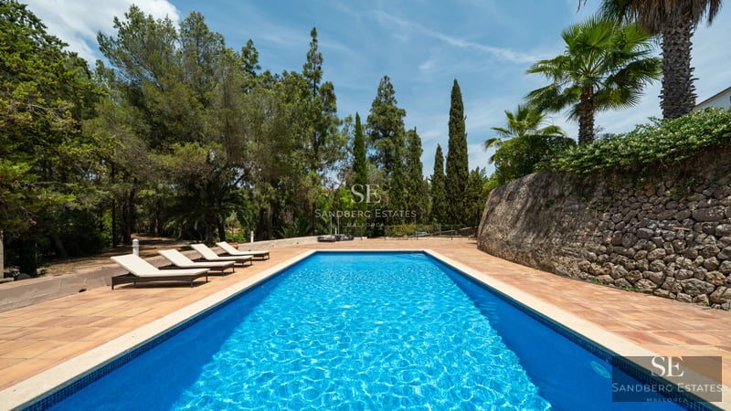 Vista exterior de villa moderna con piscina, jardín, fachada minimalista y amplios ventanales. Iluminación natural y diseño elegante.