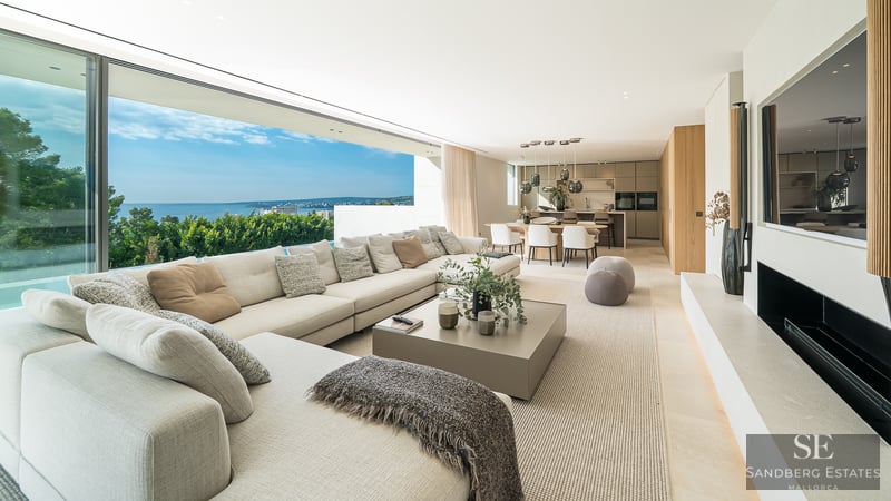 Spacious modern living room with large sectional sofa, floor-to-ceiling glass walls, and panoramic ocean views.
