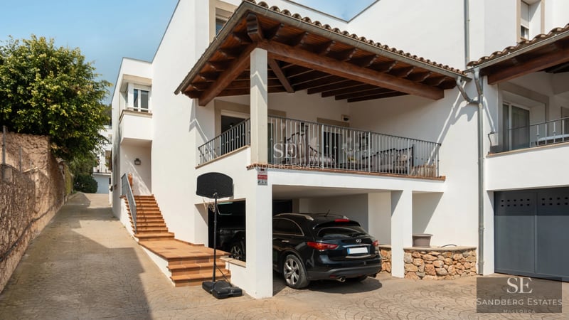Aerial view of a modern villa with a pool, lush garden, and minimalist architectural design featuring large windows.