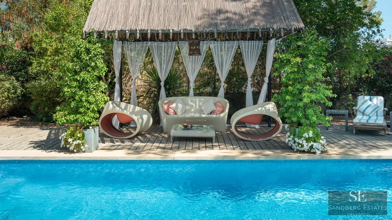 View of pool with sun loungers, lush garden, and modern facade. Minimalist architecture with large windows and neutral colors.