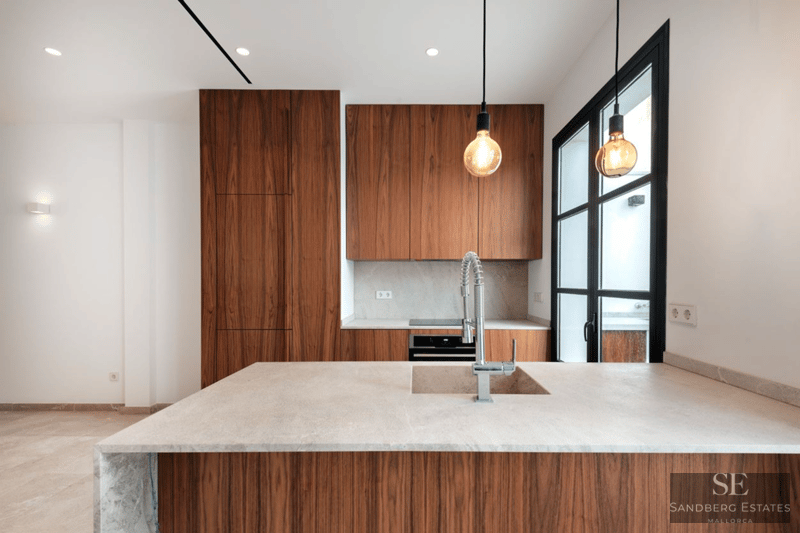 Moderne Küche mit eleganten Walnussholzschränken, Steininsel mit Spülbecken und Designer-Pendelleuchten.