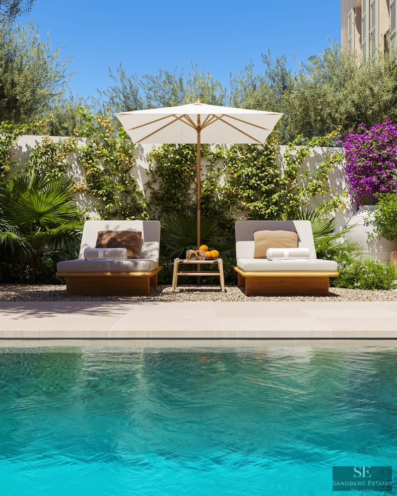Dos elegantes tumbonas con sombrilla blanca junto a una piscina turquesa y plantas mediterráneas.