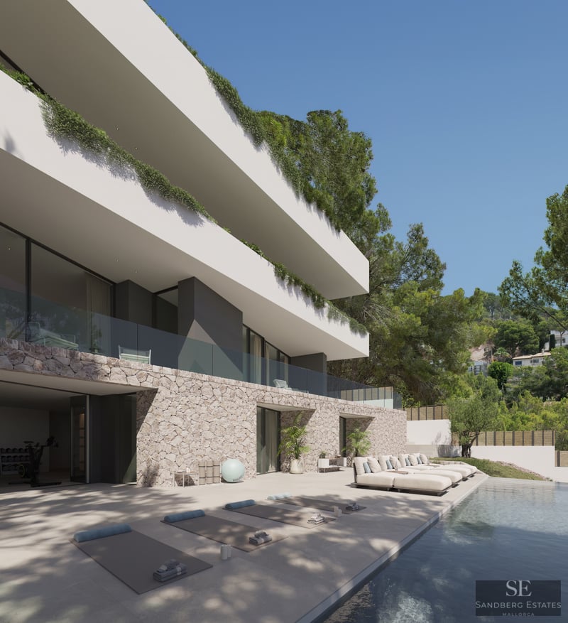 Pool terrace with sun loungers and yoga mats in front of a modern stone and white villa.