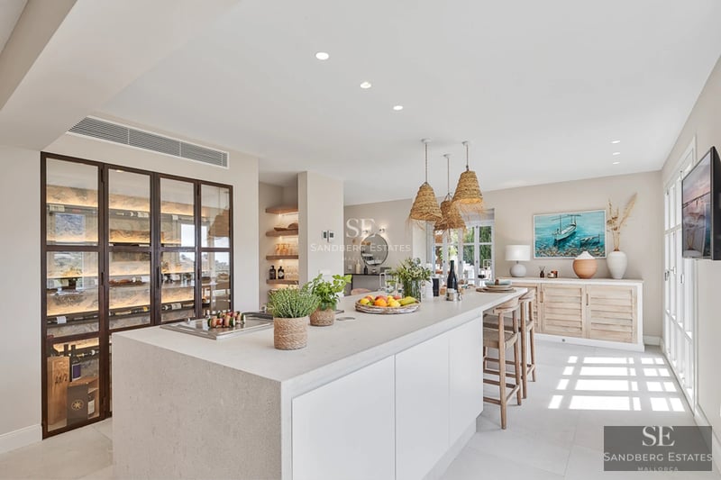 Spacious living room with large windows, light wood floors, and minimalist decor. Panoramic sea views from the balcony.