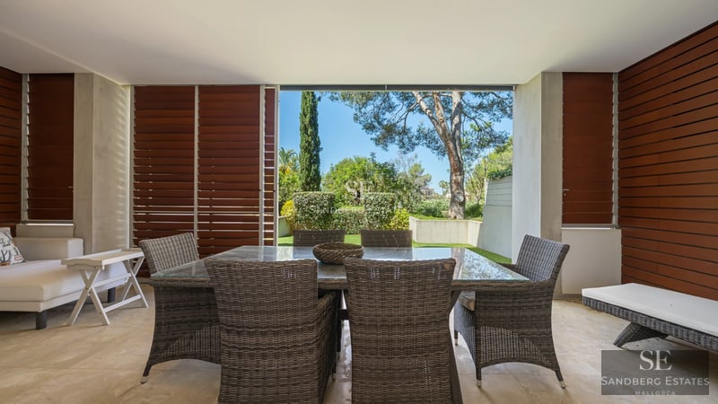 Exterior of a modern villa featuring a reflecting pool, expansive glazing, and minimalist landscaping. Warm ambient lighting.