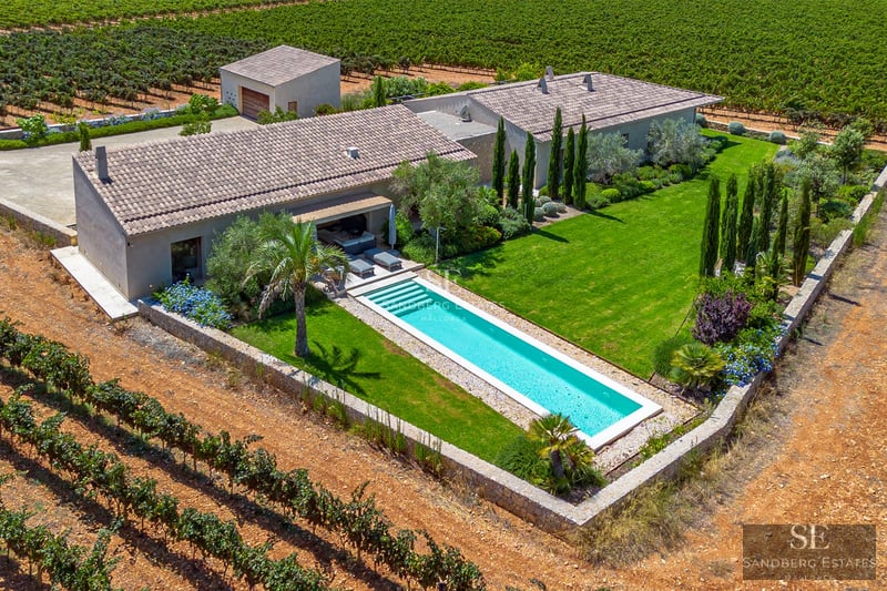 Exterior view of a modern villa featuring a pool, garden, and large windows. Minimalist architecture with natural textures.