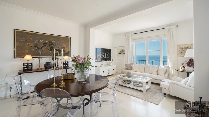 Spacious living room with sea views, balcony, and modern design. Light wood floors, gray sofas, and design details.