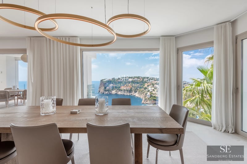 Spacious living room with floor-to-ceiling windows, modern sofas, coffee table, and panoramic sea views. Elegant and bright design.