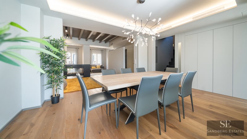 Geräumiges modernes Esszimmer mit einem großen Holztisch, grauen Stühlen und einem Designer-Kronleuchter.