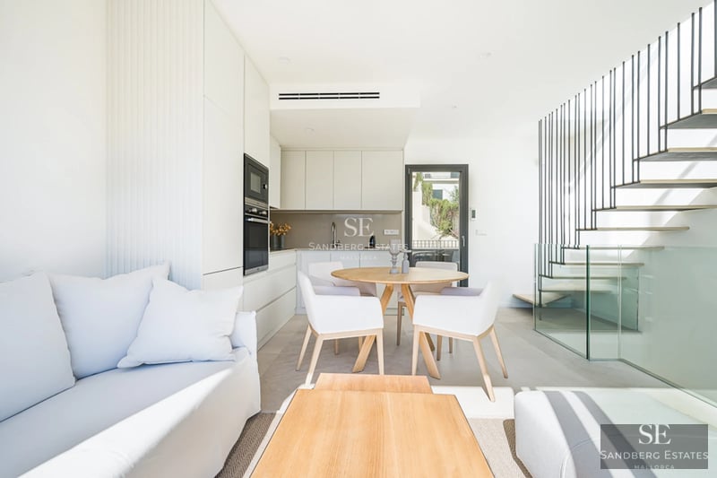 View of a modern villa featuring an infinity pool, lush garden, and large windows. Minimalist architecture and manicured landscaping.