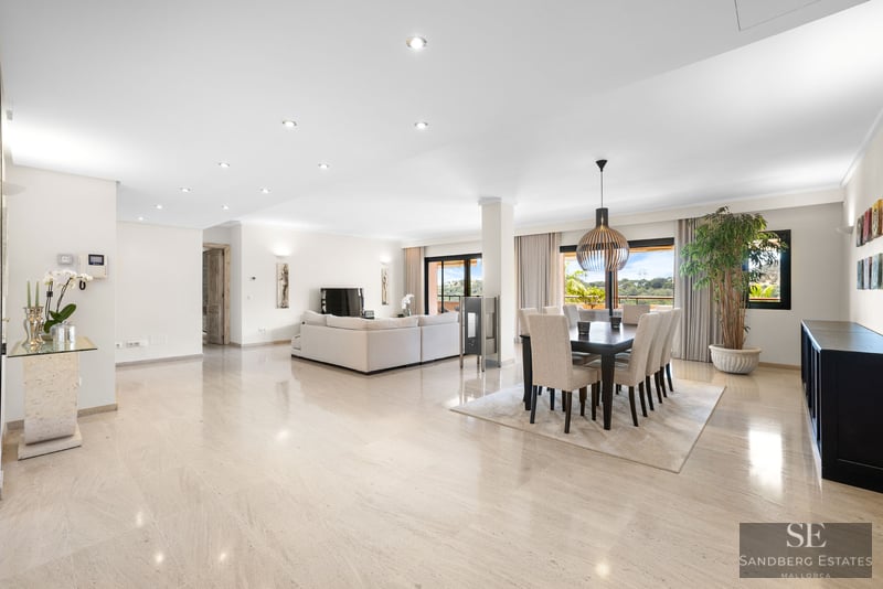 Intérieur lumineux à aire ouverte avec sols en marbre poli, un grand canapé blanc et une salle à manger moderne.