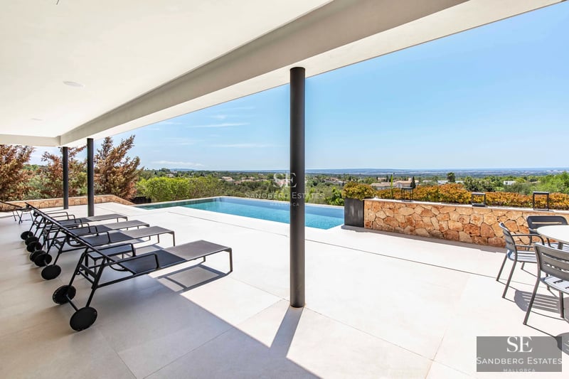 Aerial view of a modern villa with infinity pool, lush garden, and spacious terraces. Minimalist architecture and luxury finishes.