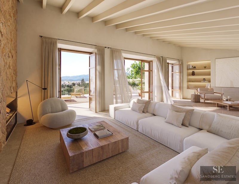 Salón espacioso con sofás blancos, pared de piedra, vigas de madera y terraza con vistas a la montaña.