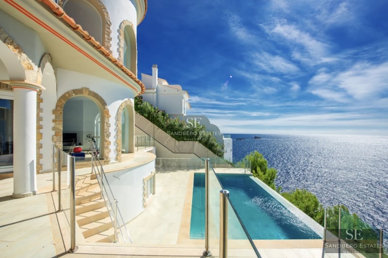 Exterior view of a modern house featuring a swimming pool, gardens, and large windows providing natural light. Minimalist architecture.