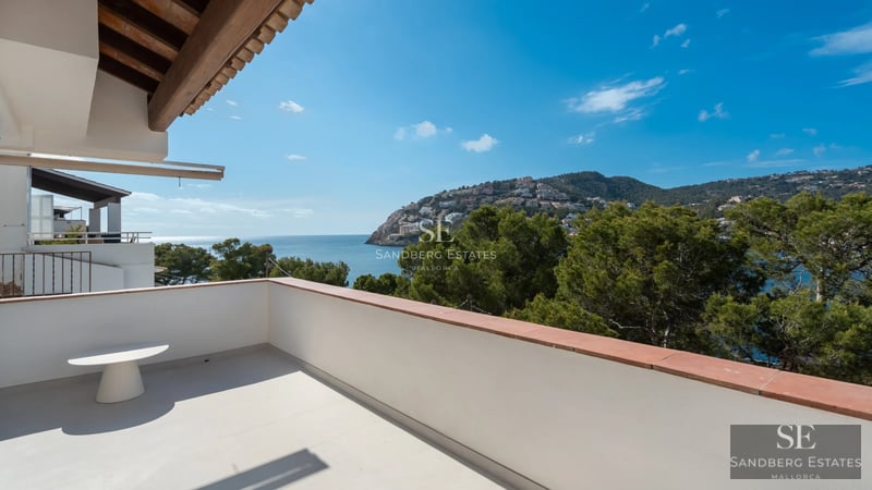 Spacious balcony with sea view, modern furniture, glass railing and wooden floor, part of a luxury apartment.