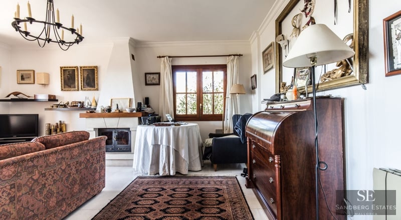 Salón acogedor con sofá estampado, chimenea de piedra, alfombra oriental y escritorio de madera antiguo.