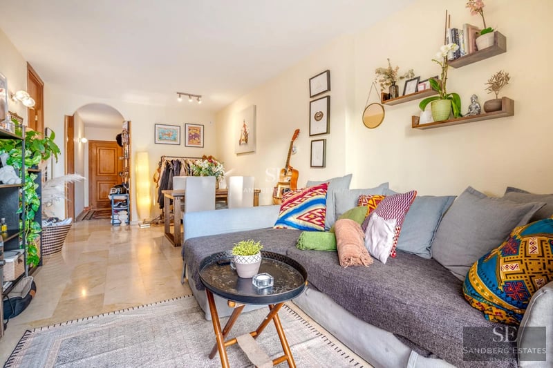 Salon lumineux avec grandes baies vitrées donnant sur piscine. Canapé modulable beige, tapis texturé et décoration minimaliste. Design moderne et élégant.