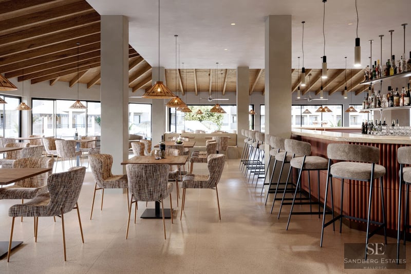 Modern bar with wooden beamed ceiling, wicker pendant lights, and upholstered bar stools.