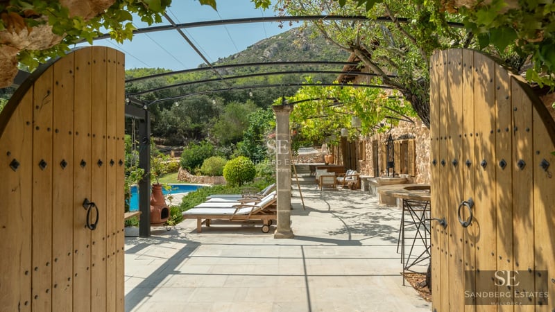 View of pool surrounded by lush greenery, featuring a wooden deck and minimalist modern architecture in the background.
