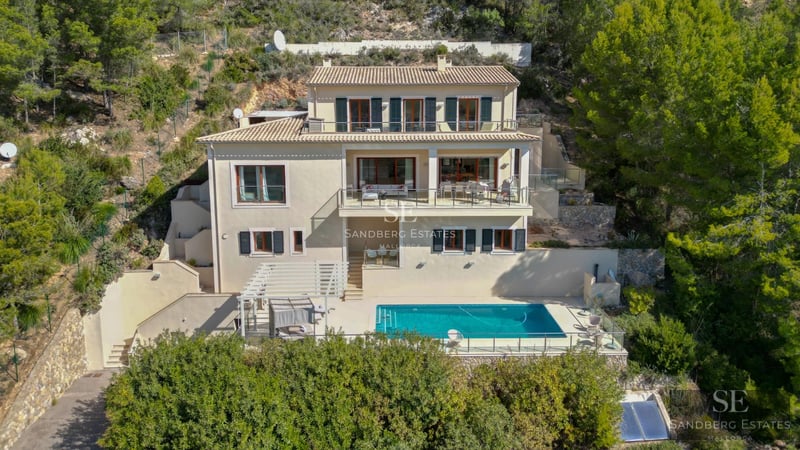 Balcony view with glass railing, wooden floor, lush greenery, and sea view. Modern elegance.