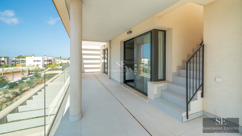 Spacious balcony with sea view. Modern outdoor furniture, glass railing, and tiled floor. Contemporary design.