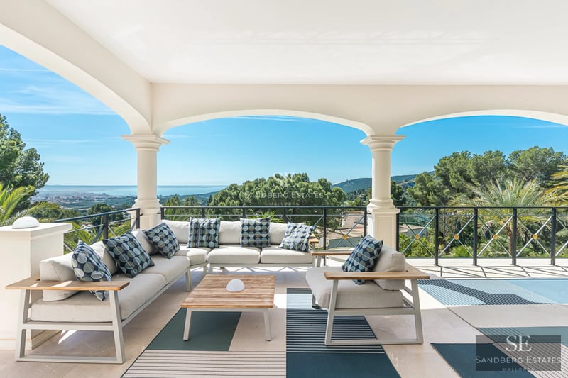 Spacious sea view balcony with modern furniture, glass railing, gray tile flooring, and retractable awning.