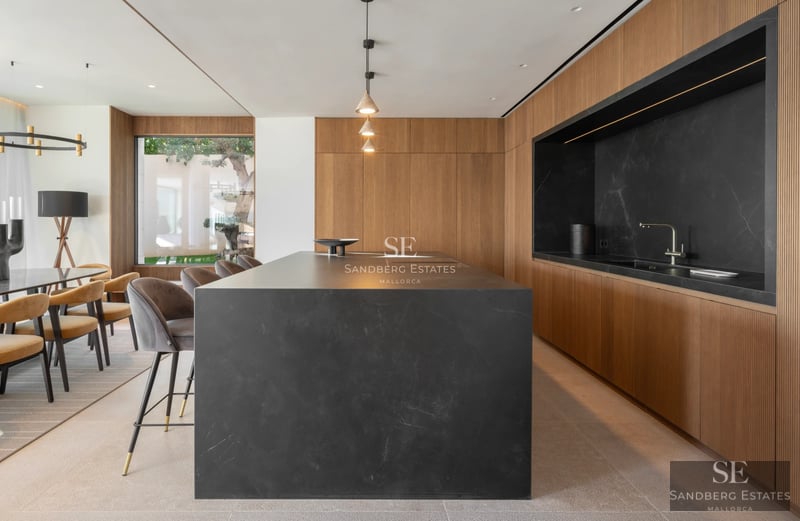 Vista de una moderna villa con piscina infinita, tumbonas, palmeras y arquitectura minimalista. Iluminación natural y colores neutros.