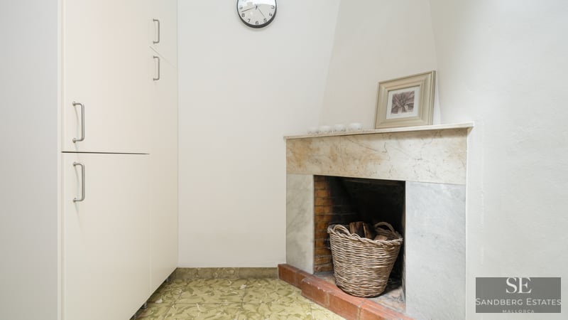 Innenecke mit Marmorkamin, Weidenkorb für Brennholz und hohem weißen Schrank.