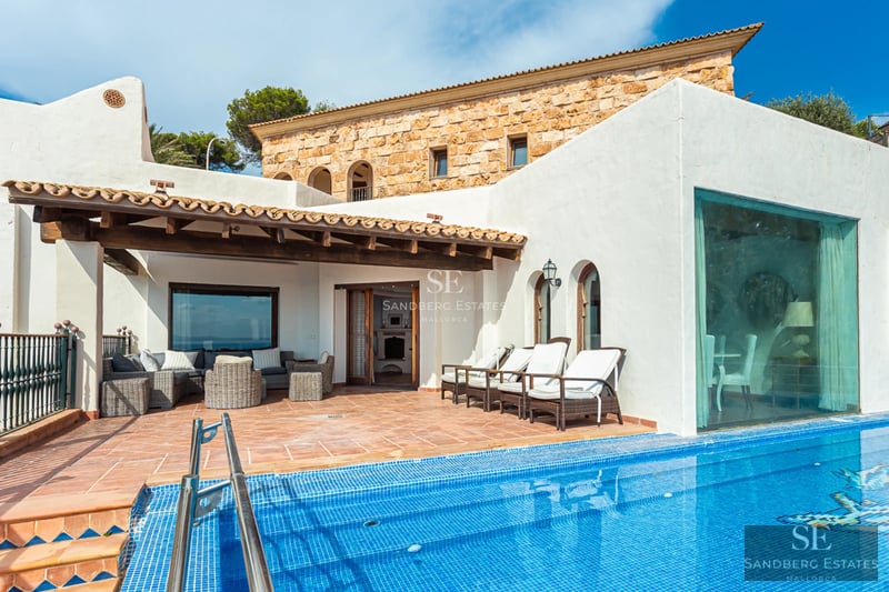 Vaste terrasse avec piscine à débordement et vue panoramique. Design moderne, mobilier d'extérieur élégant et végétation luxuriante.