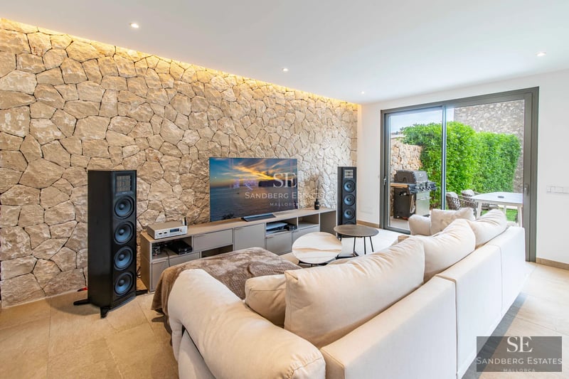 Exterior view of a modern villa featuring an infinity pool, lush garden, and contemporary architecture. Warm lighting.