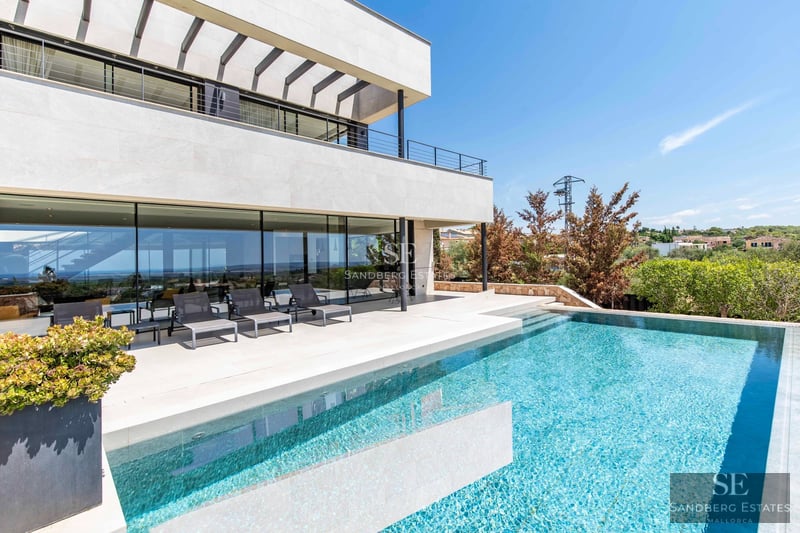 Expansive terrace with infinity pool, sun loungers, and panoramic views. Modern design with high-end finishes and lush greenery.