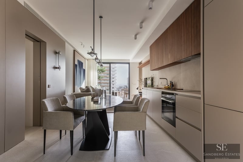 Modern Designer Dining Area and Kitchen Contemporary dining room with oval black table, grey chairs, and a minimalist integrated kitchen with balcony access.