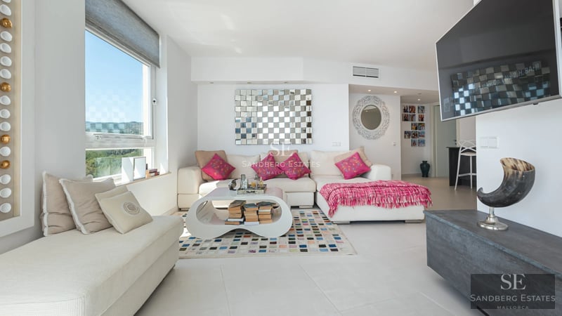 Aerial view of a modern residence featuring an infinity pool, expansive terraces, and lush surrounding greenery.