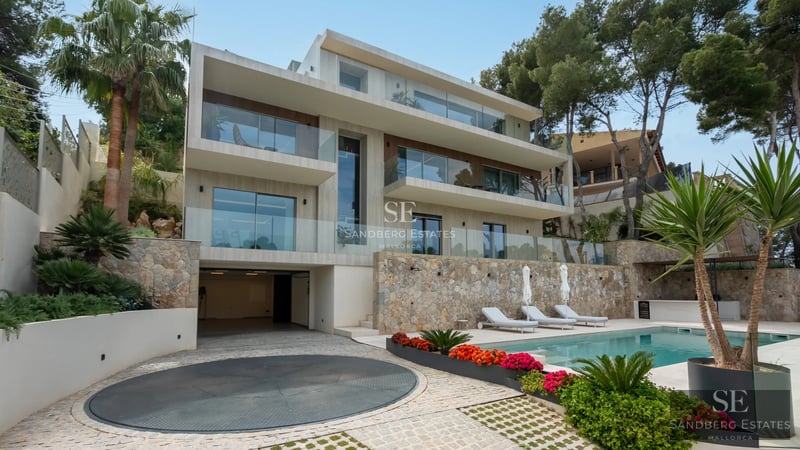 View of infinity pool, lounge chairs, and lush greenery. Modern design. Soft lighting creating a relaxing atmosphere.