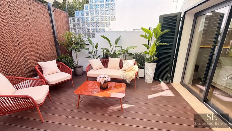 Terrace featuring wood decking, terracotta-colored outdoor furniture, and decorative plants under bright natural light.