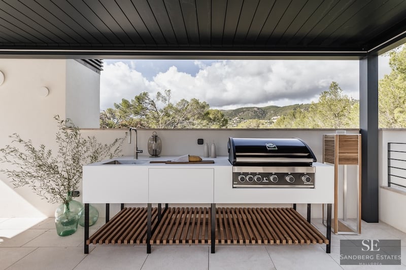 Sleek Modern Outdoor Kitchen and Terrace Modern outdoor kitchen with professional BBQ, sink, and white cabinetry on a terrace overlooking a mountain landscape.