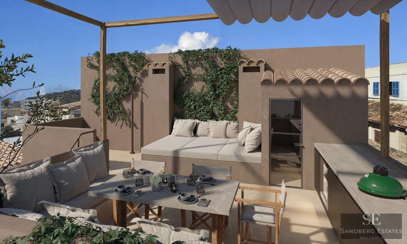 Sun-drenched rooftop terrace with a stone dining table, integrated daybed, outdoor kitchen, and climbing vines on stucco walls.