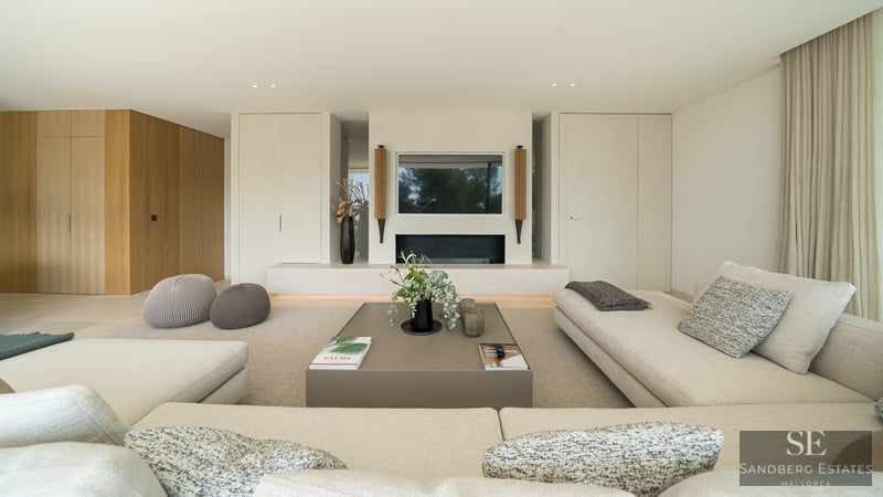 Spacious living room featuring beige sofas, an integrated fireplace, and a modern coffee table in neutral tones.