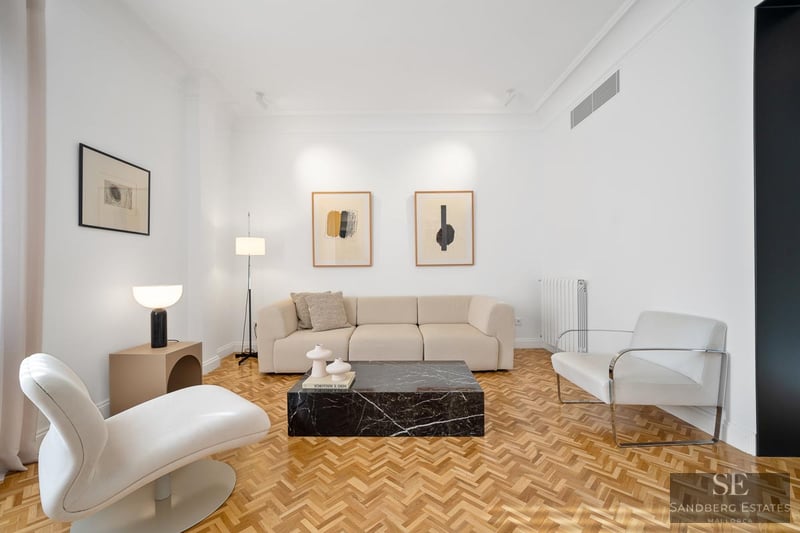 Bright living room with white walls, herringbone wood floor, beige sofa, and a striking black marble coffee table.