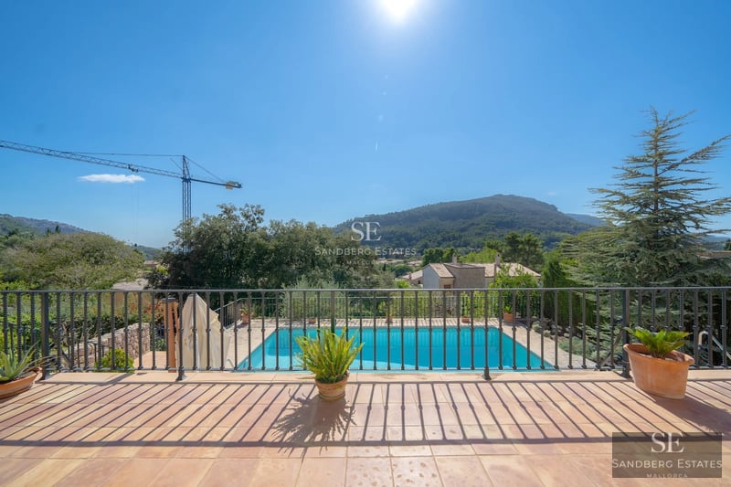 Exterior view of a modern villa featuring a pool, lush garden, and minimalist architecture. Large windows and spacious terrace.