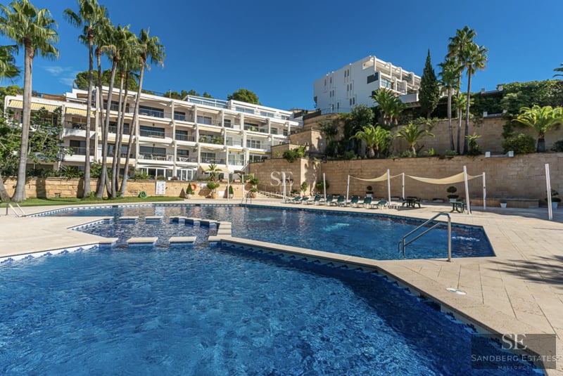 Vista de villa moderna con piscina infinita y jardín exuberante. Diseño arquitectónico elegante y paisajismo cuidado.