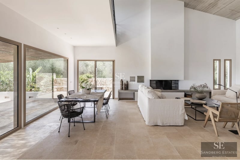 View of a luxury villa featuring an infinity pool, surrounded by lush gardens and expansive terraces. Modern design with window walls and natural stone.