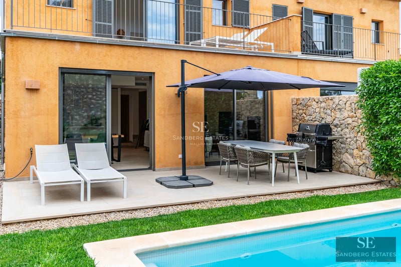 Exterior view of a luxurious, modern villa featuring a pool, manicured garden, and expansive terraces. Minimalist and bright architecture.