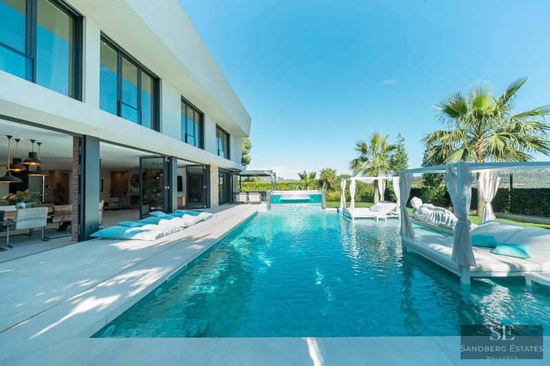 Exterior view of a modern villa with a pool, garden, and spacious terraces. Sleek design and high-quality finishes.