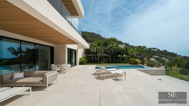 Spacious and bright living room featuring a fireplace, panoramic windows, and modern designer furniture. Breathtaking views.