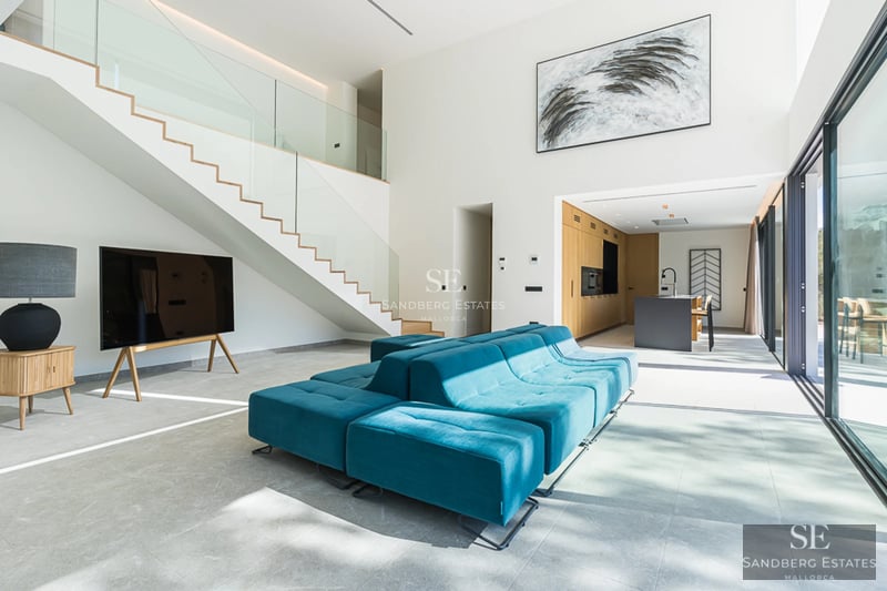 Utsikt över infinitypool med solstolar, parasoller och lummiga trädgårdar. Modern design med stämningsbelysning.