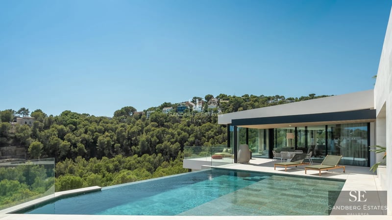 View of a modern villa with infinity pool, terrace, and large windows. Minimalist design with high-quality finishes.