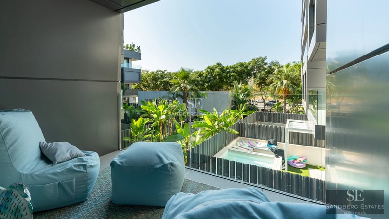 Spacious living room featuring expansive windows, light wood flooring, modern fireplace, and designer furniture. Abundant natural light.